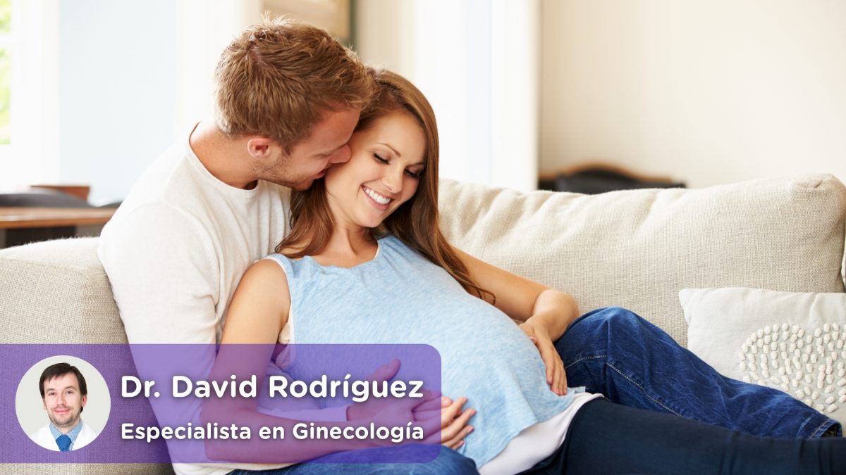 Pareja con mujer embarazada, relajados en el sofa juntos mientras esperan el nacimiento de su bebé